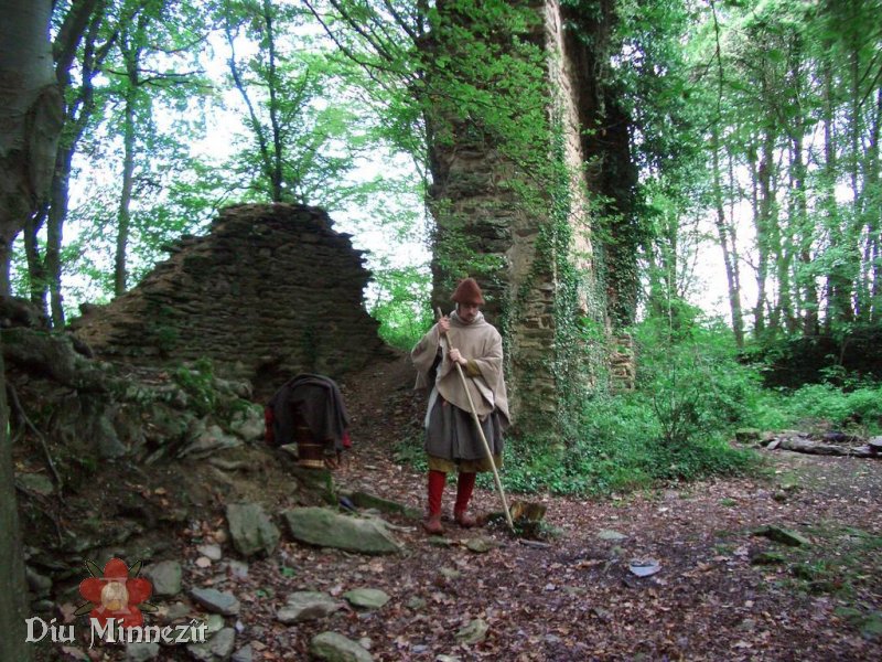 Pilger in hochmittelalterlicher Kleidung inmitten der Ruine eines Klosters aus dem Hochmittelalter