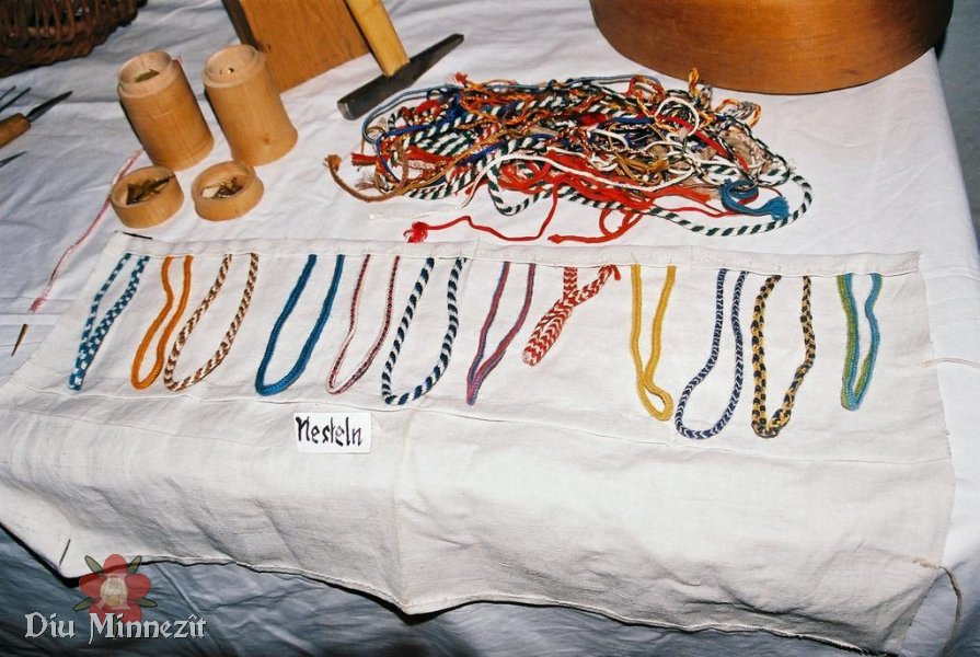 Auszug aus der Musterauslage eines spätmittelalterlichen Nestelmachers: verschiedene Fingerschlaufen Muster von Nesteln in pflanzlich gefärbter Wolle